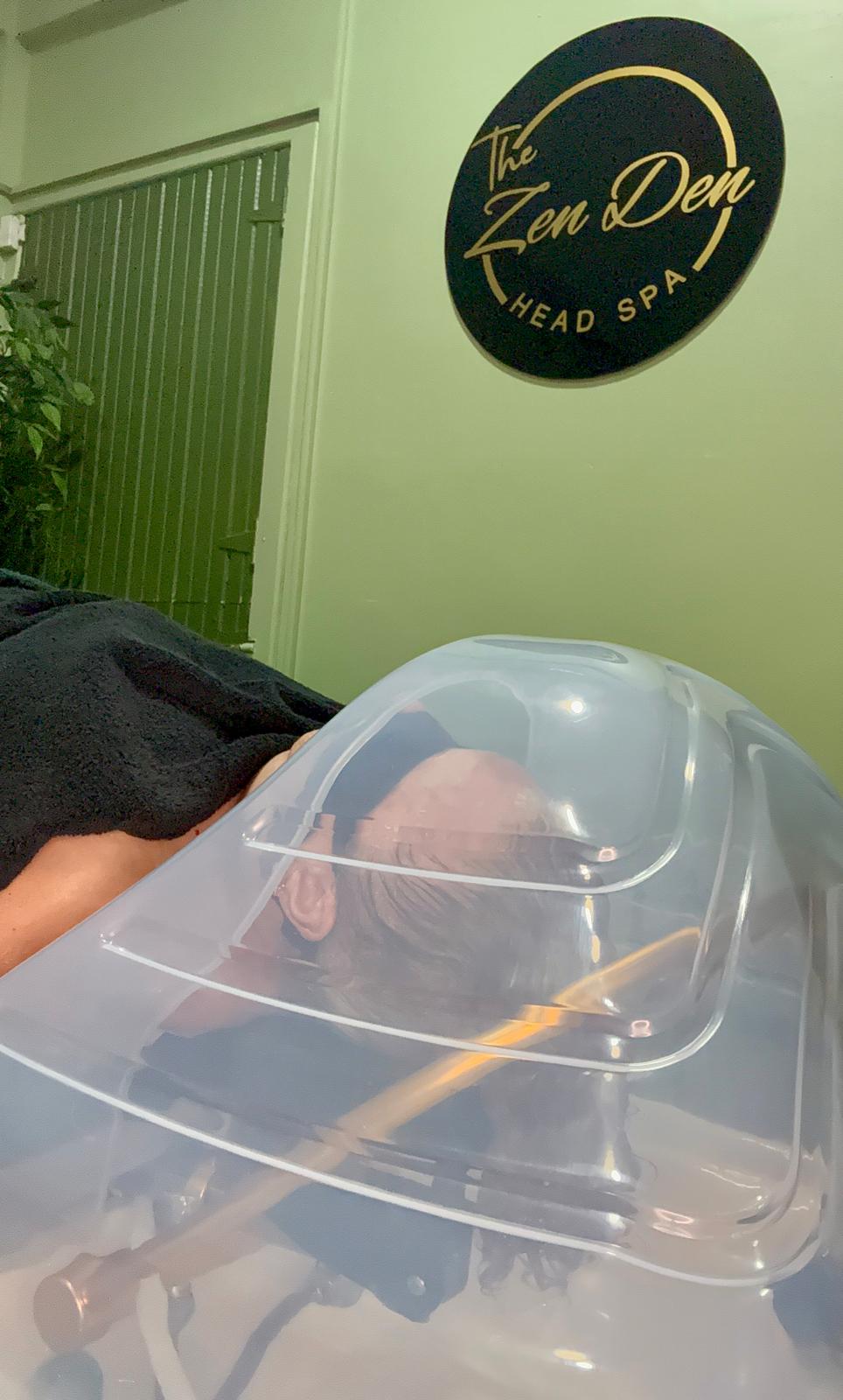Client receiving a steam-based head spa treatment in a calm wellness room.