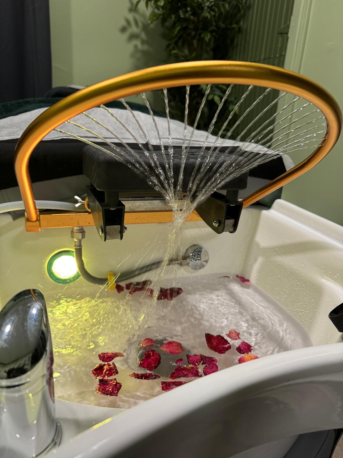 Close-up of the signature water arch and basin lighting with petals for a luxury spa ambiance.